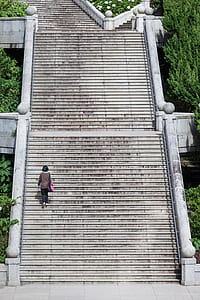 woman wearing gray jacket and pink bag walking on stairs thumbnail
