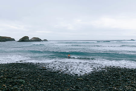 person standing on shoreline facing the crashing sea waves thumbnail