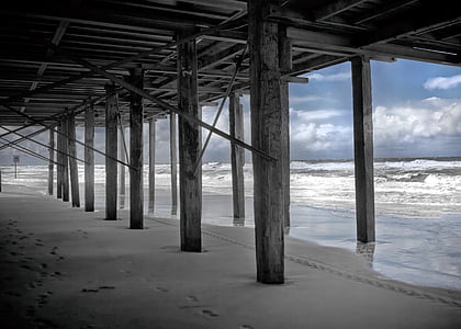 gray wooden bridge stand beside ocean waves during daytime thumbnail