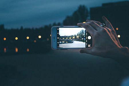 Woman photographer taking a photo with her iPhone camera at night thumbnail