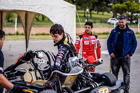 Two Motorcycle Racers Standing in Front of Motorcycles thumbnail