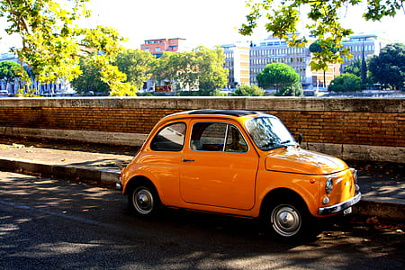 orange Volkswagen beetle car parked beside wall thumbnail