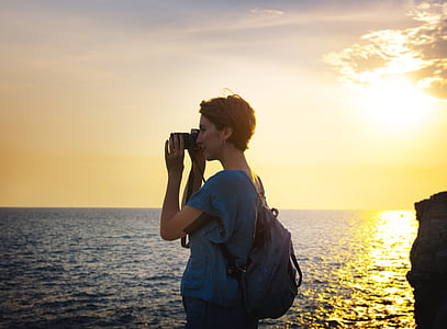 standing woman with blue shirt at sunset thumbnail