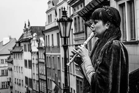 woman playing flute near buildings thumbnail