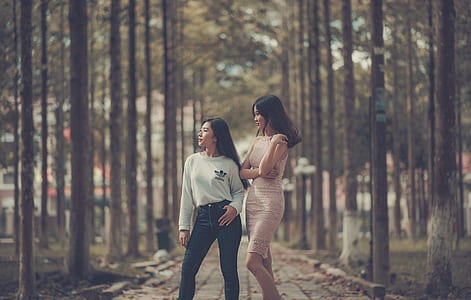 Two Woman Standing on Sidewalk Near Trees thumbnail