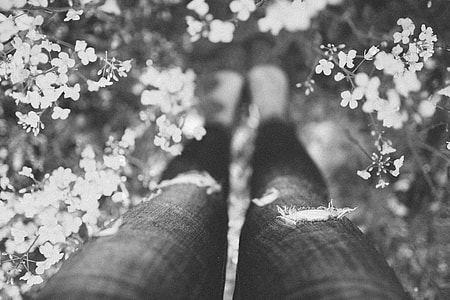 grayscale photography of person standing near petaled flowers thumbnail