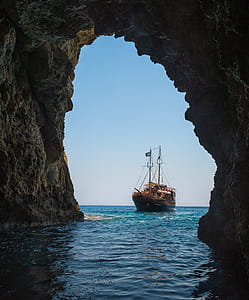 Brown Boat on Body of Water Towards Tunnel thumbnail