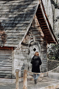 person walking beside grey wooden house thumbnail