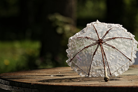 shallow focus photography of white umbrella on brown wooden spool table thumbnail
