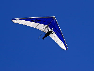 blue and white hang glider on flight under clear blue sky thumbnail