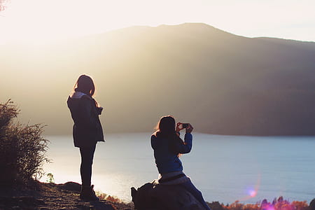 woman sitting on rock while taking photo thumbnail