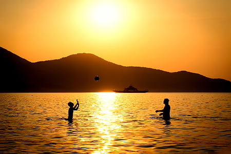 silhouette of two people playing ball on water during sunset thumbnail