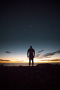 silhouette of man facing body of water at golden hour thumbnail