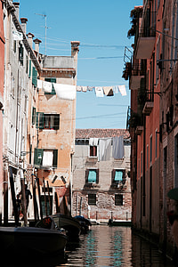 clothes hang on rope between concrete building above body of water during daytime thumbnail