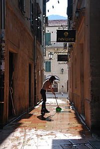 woman holding mop beside house during daytime thumbnail