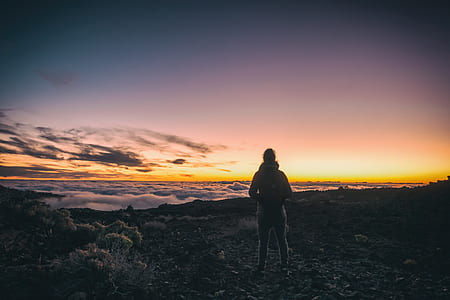 person standing on top of a mountain above the clouds during sunset thumbnail