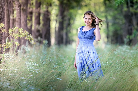 selective photography of woman wearing blue and black tank dress in green grass field thumbnail
