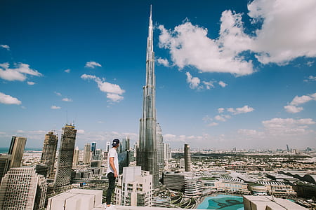 man standing alone on top of building looking at the city's tallest building during daytime thumbnail