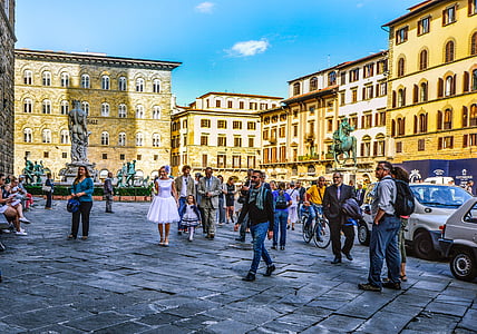 people walking between brown concrete buildings thumbnail