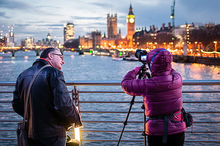 man standing beside person taking a picture of body of wate r thumbnail