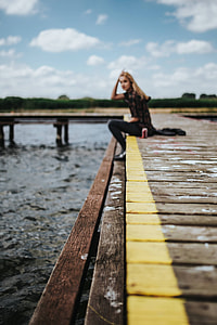 Beautiful blonde woman on a wooden pier by the lake thumbnail