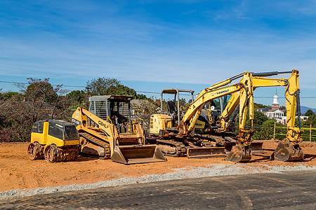 four yellow heavy equipments near trees thumbnail