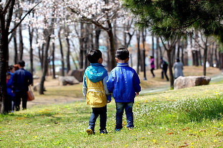 two toddlers standing side-by-side on green grassy plain during day thumbnail