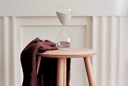clear hourglass on beige wooden stool thumbnail