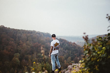 man standing near cliff facing mountain thumbnail