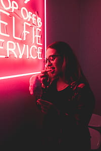 woman standing behind LED signage on wall while eating ice cream thumbnail