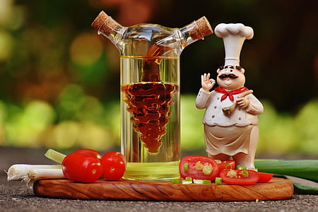 Chef Figurine Beside Clear Glass Bottle and Tomatoes thumbnail