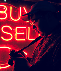 man in cap standing beside buy and sell neon sign thumbnail