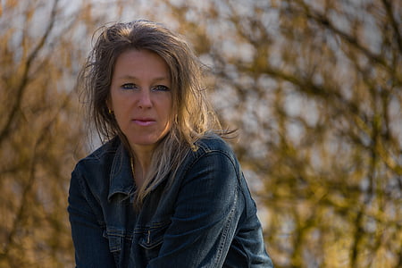 brunette haired woman in blue denim jacket under a tree thumbnail