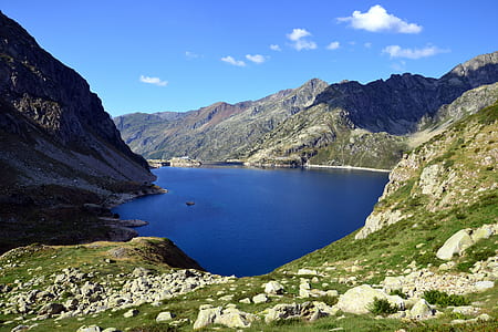 Mountain With Green Grass Beside Body of Water Under Blue Sky during Daytime thumbnail
