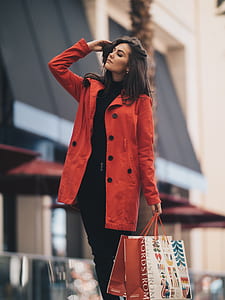 woman wearing red long coat holding paper bags thumbnail