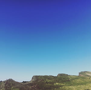 green hills under blue skies at daytime thumbnail