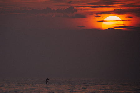 person holding rod on body of water during golden hour thumbnail