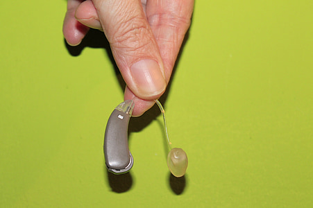 person holding brown hearing aid thumbnail