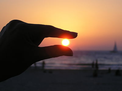 silhouette photo of sunset and person's hand thumbnail