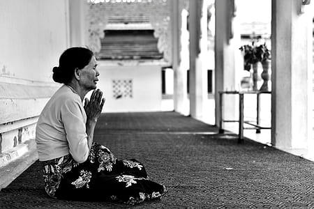 grayscale photo of woman sitting while in praying hands thumbnail
