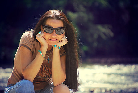 woman in brown crew-neck T-shirt sitting near body of water thumbnail