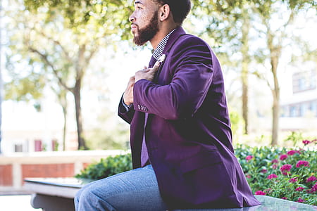 man holding purple blazer sitting in front of pink flowers thumbnail