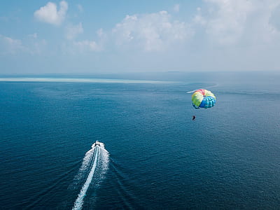 person on parachute near water and speedboat during daytime thumbnail
