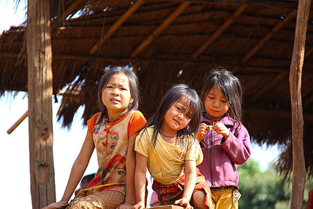 three girl beside brown house near trees thumbnail