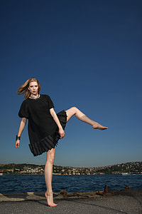 woman in black dress standing in 1 leg on floor under clear sky during daytime thumbnail