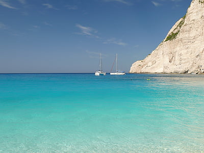 two white boat on body of water near the mountain thumbnail