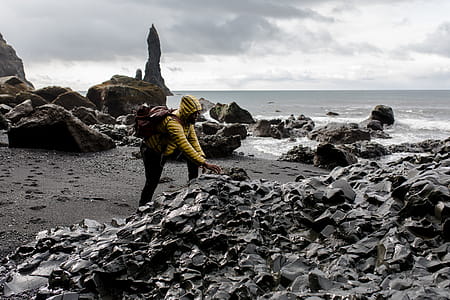Person Wearing Hoodie Touching Stone in Seashore thumbnail