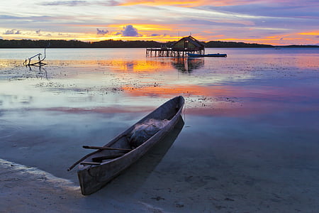 canoe docked on seashore during golden hour thumbnail