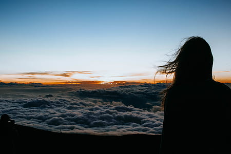 silhouette of woman standing near sea of clouds thumbnail