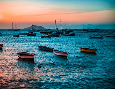 boats on body of water under orange and blue sky thumbnail